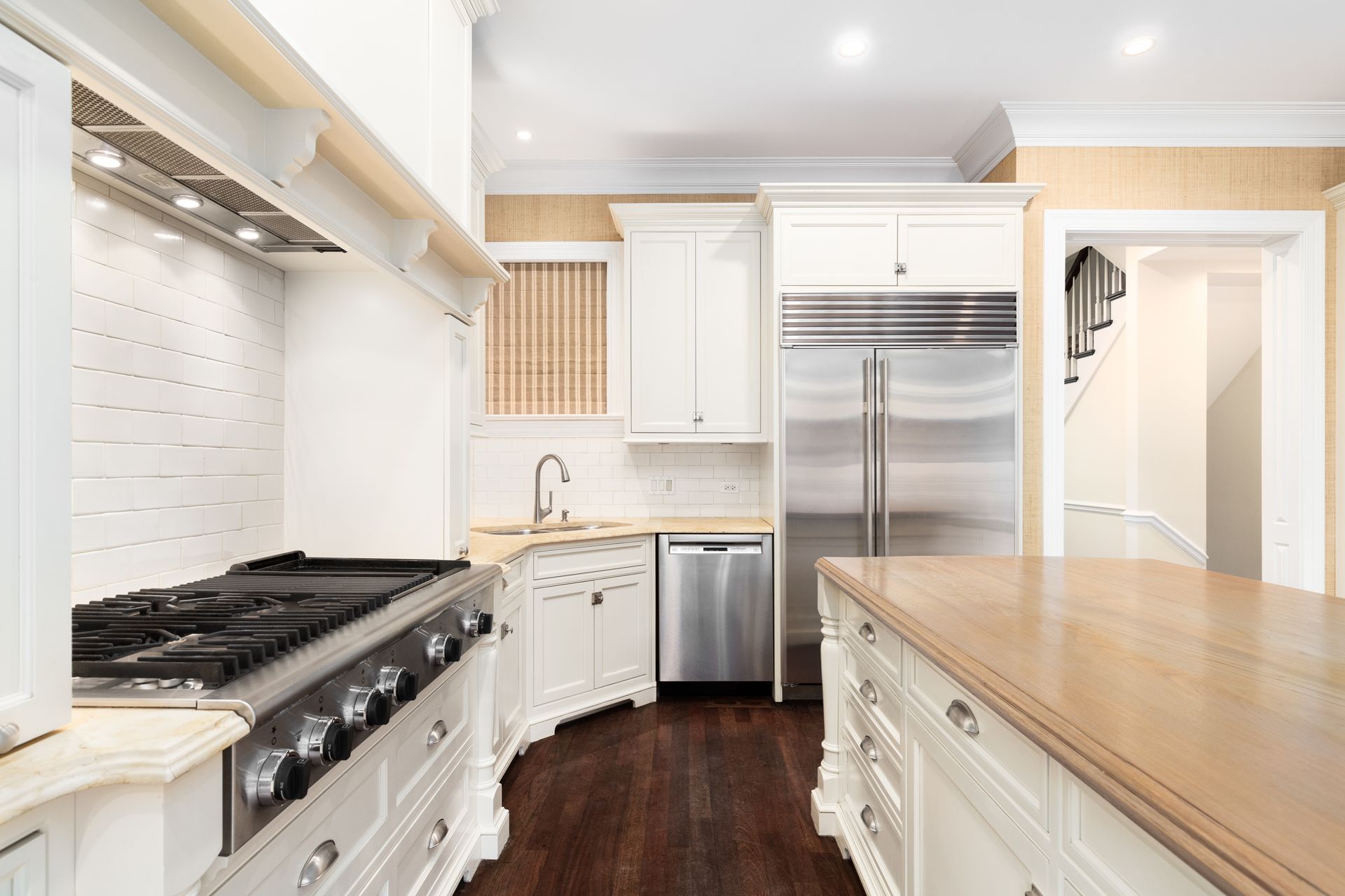 Modern kitchen with stainless steel, white cabinets, granite, and range hood.