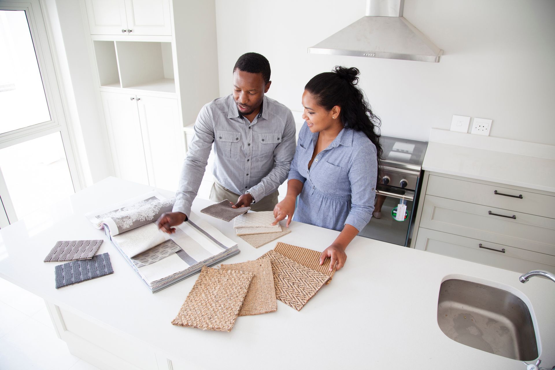 Interior designers reviewing fabric samples on kitchen island during modern home renovation work.
