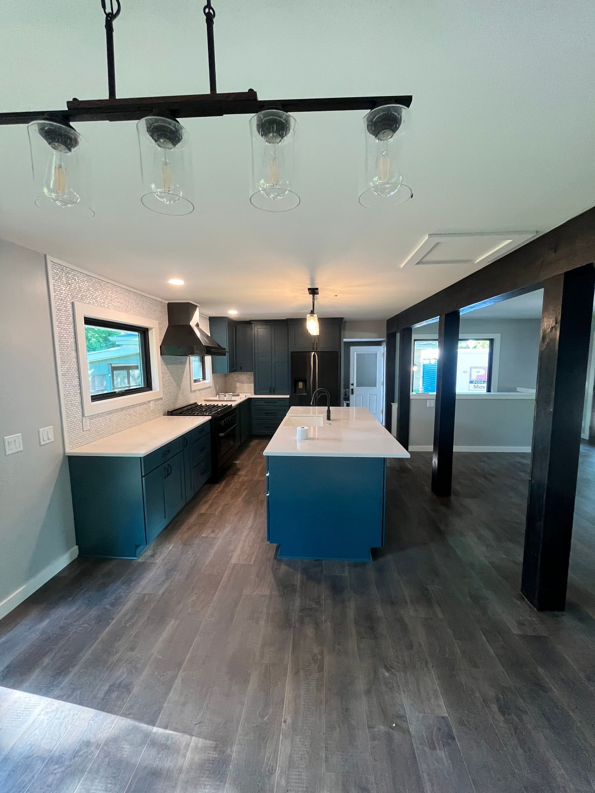Modern kitchen with teal cabinets, a large island, and dark wood flooring.
