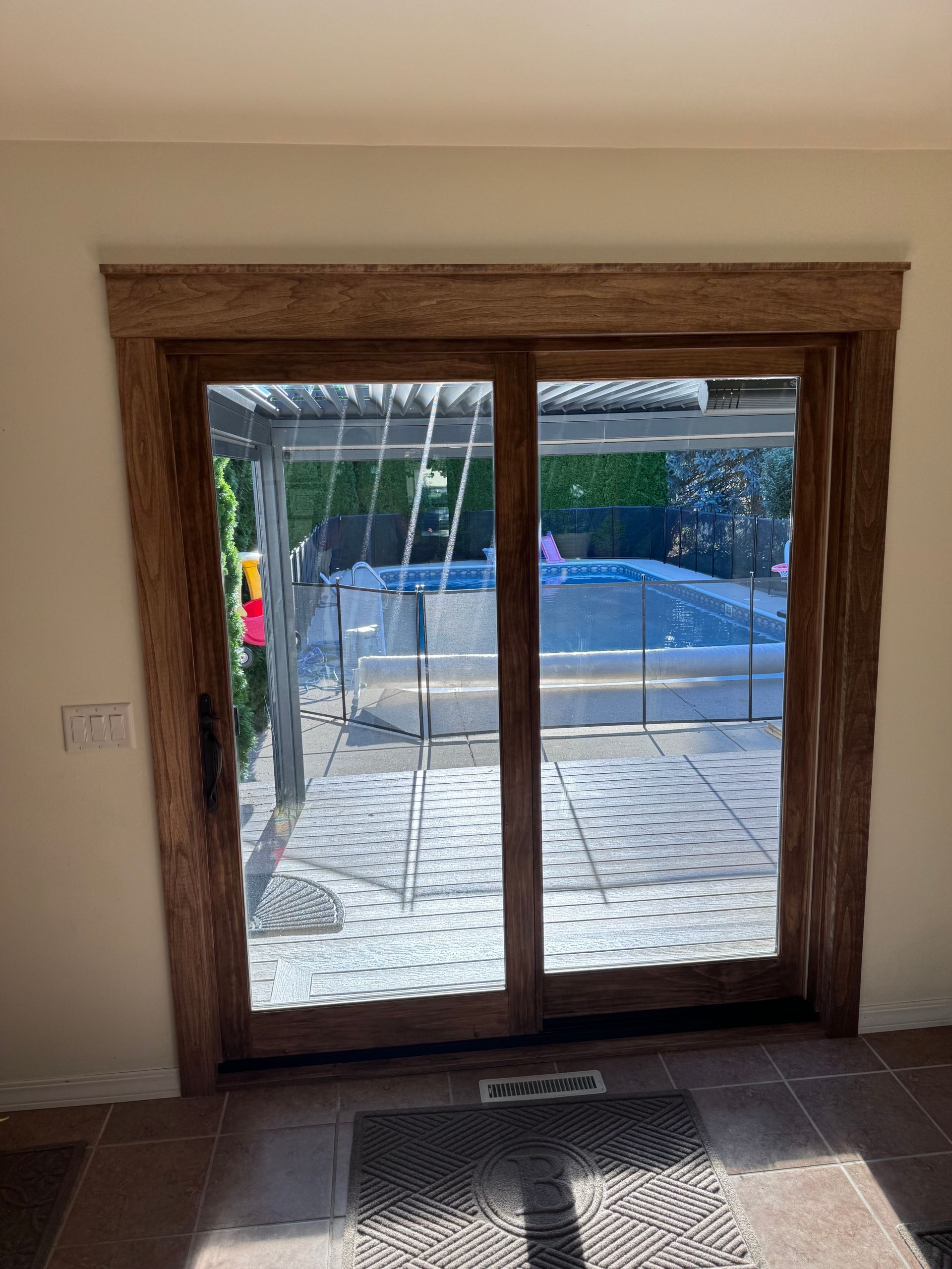 Sliding glass door framed with textured wood, overlooking a patio and pool.