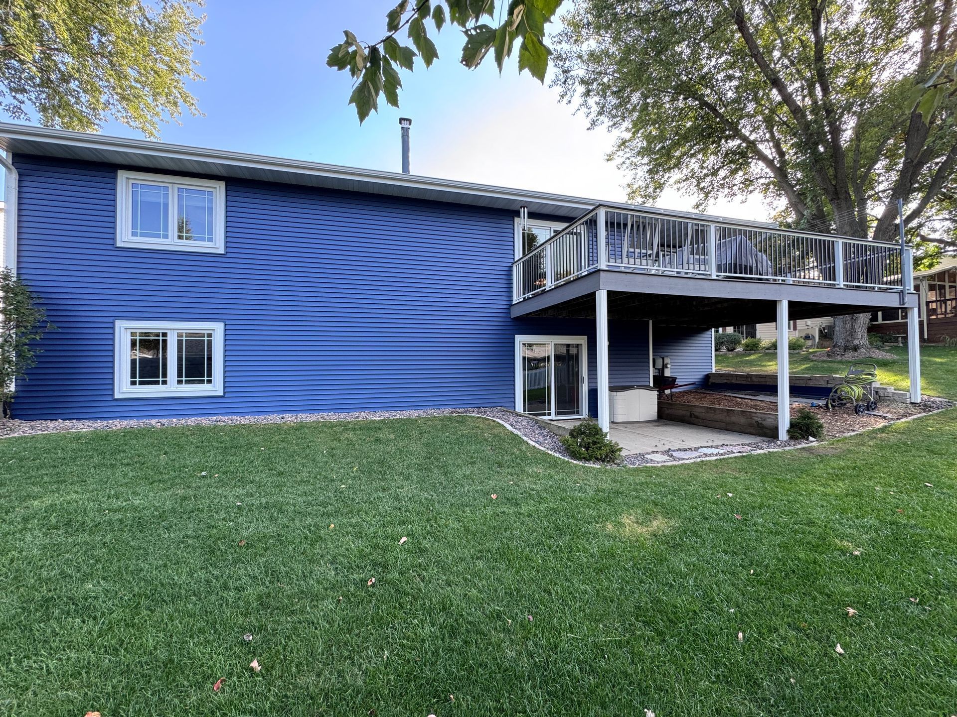 Blue house with a deck and lawn.