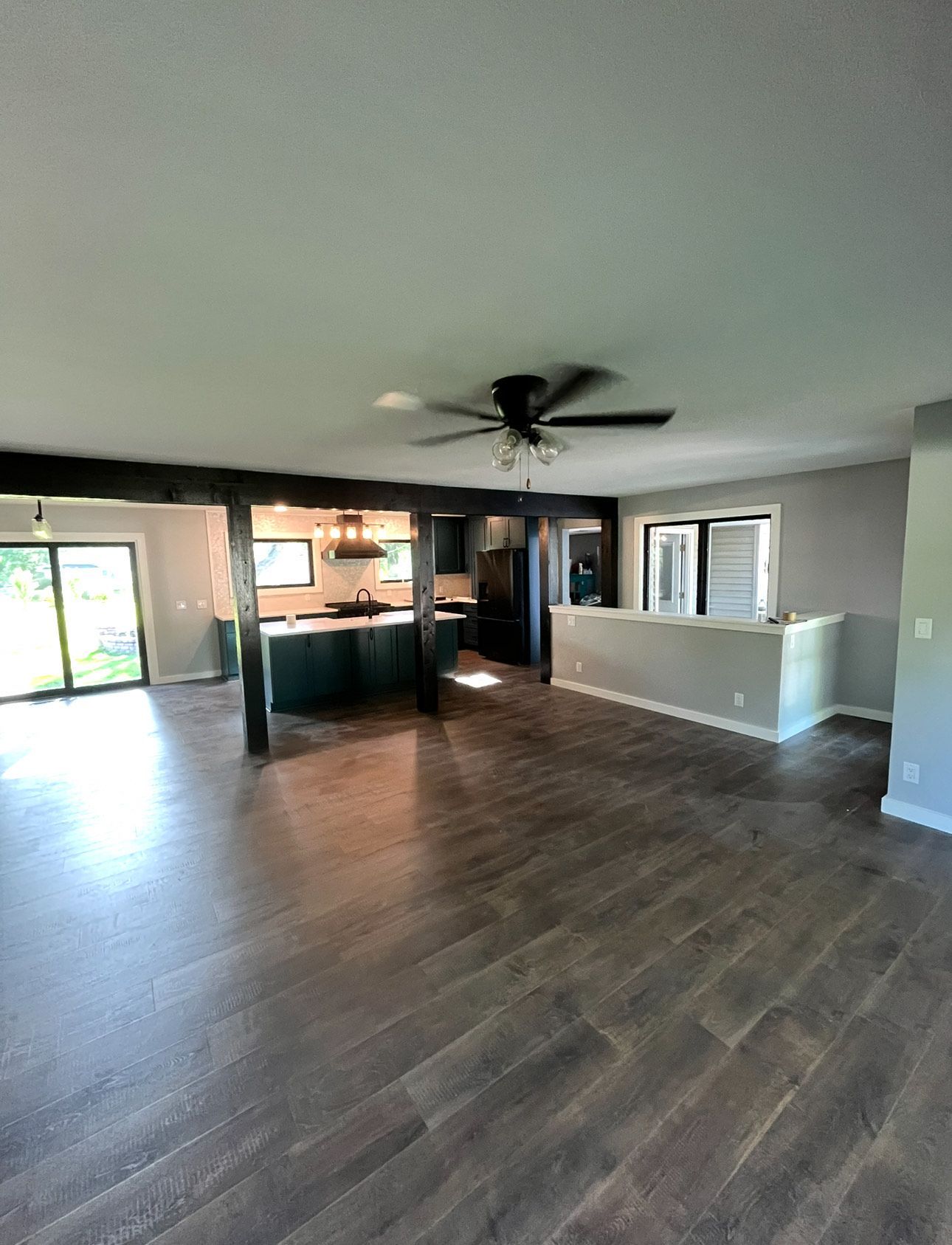 Open-concept living space with dark wood floors, kitchen with a teal island, and sliding glass doors.