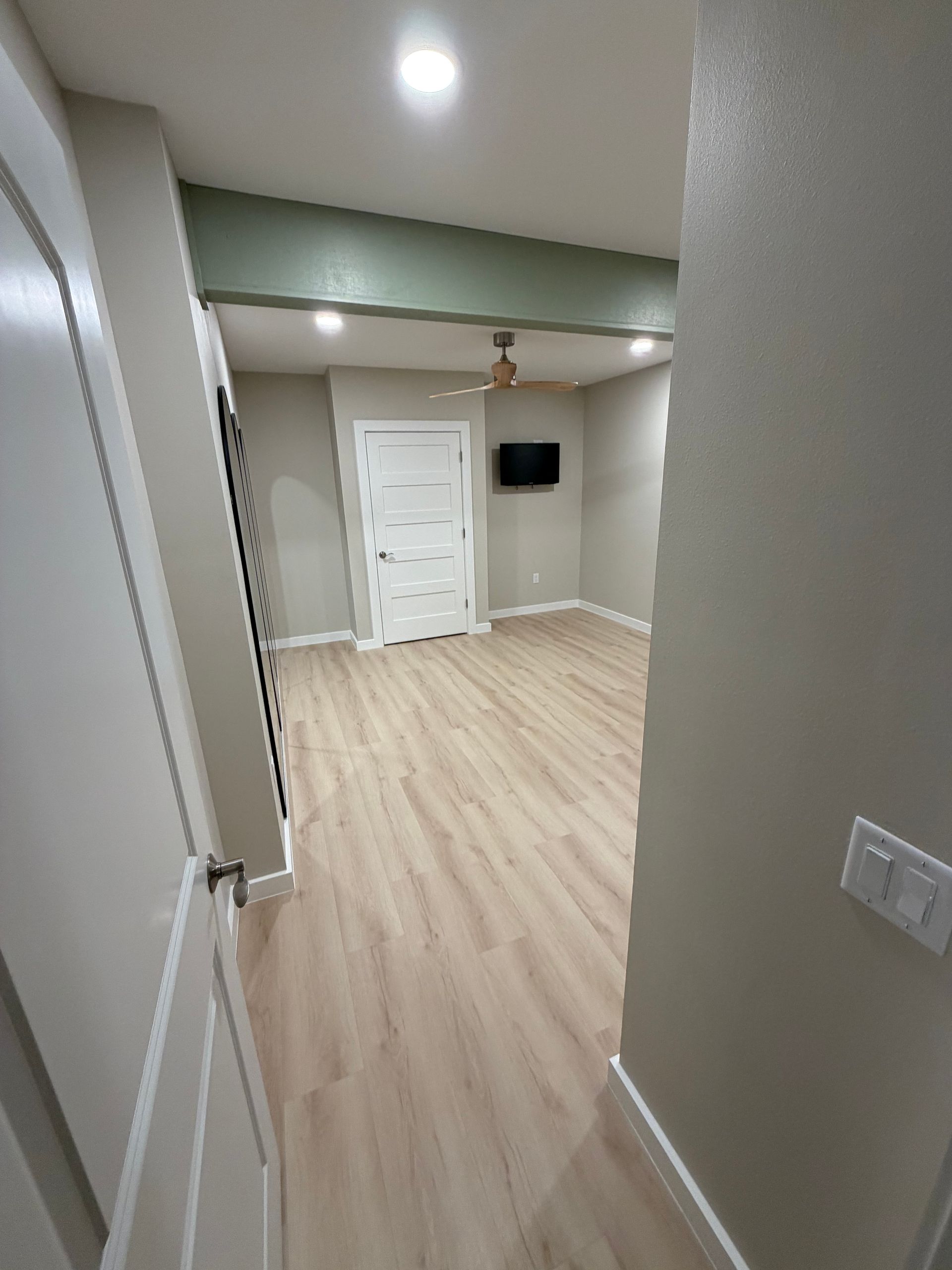A doorway leads into a room with light wood floors and gray walls. A green section is above.