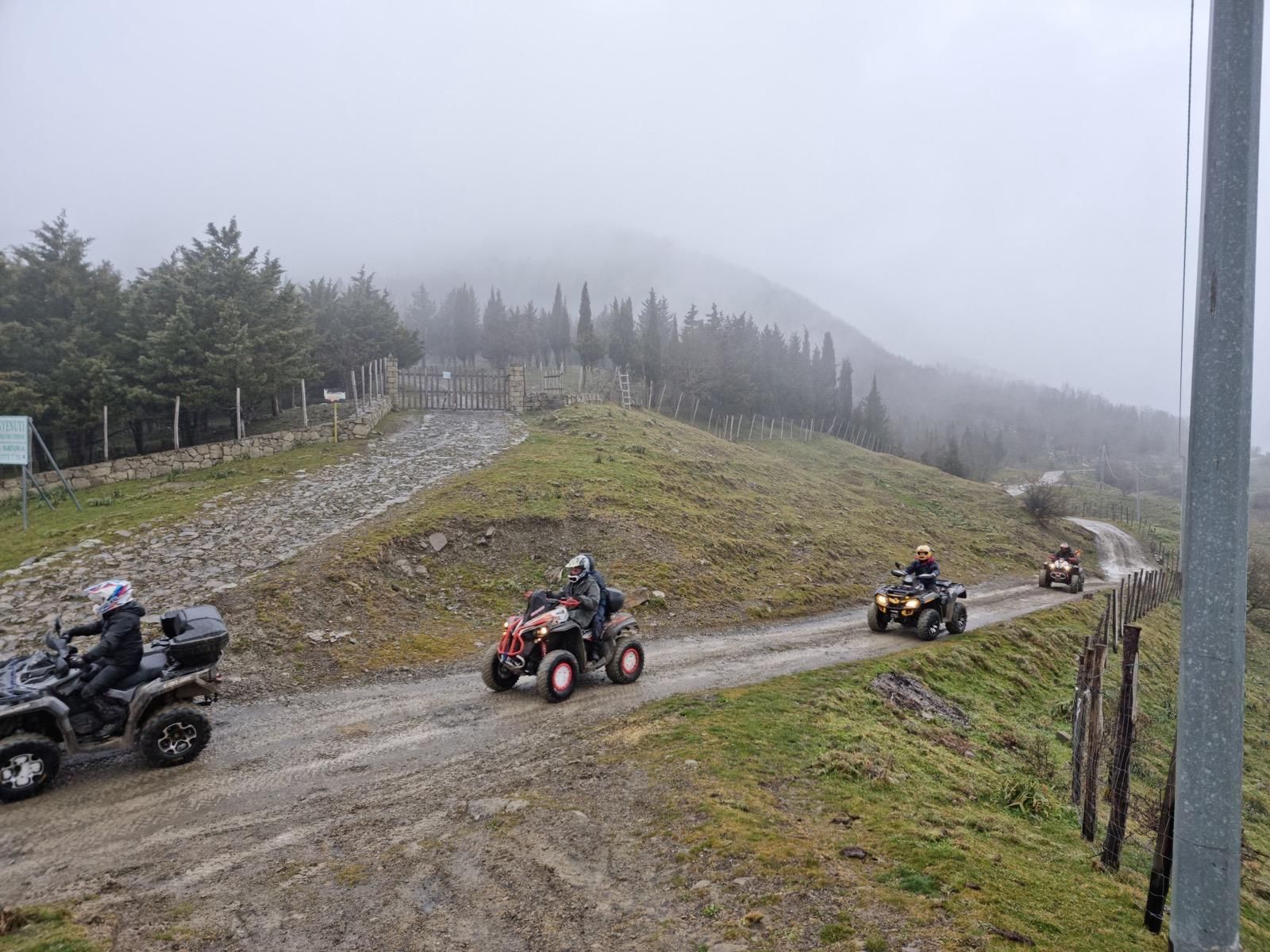 Quattro quad percorrono una strada fangosa in salita in una giornata nuvolosa.