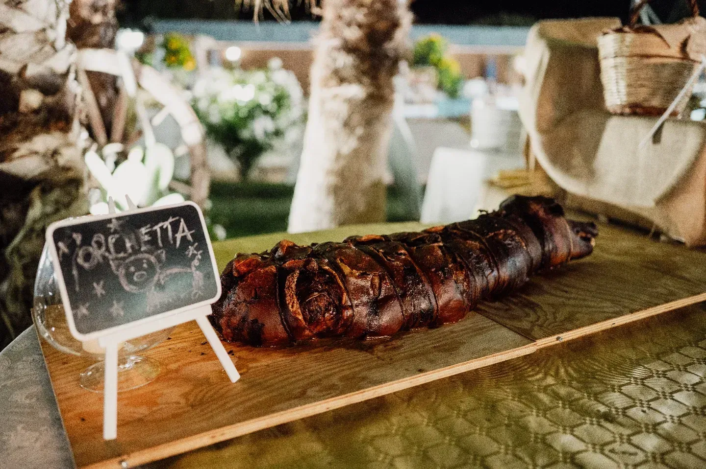 Porchetta intera arrostita su una tavola di legno, con un cartello sulla lavagna con la scritta 