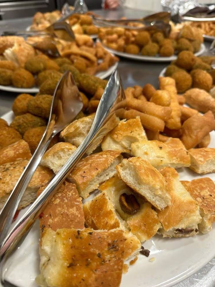 Piatti di vari antipasti fritti, tra cui pane, crocchette e frittelle di pasta, disposti su un buffet.