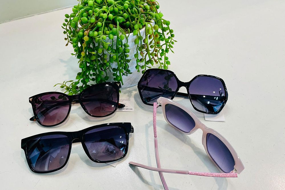 Three Pairs Of Sunglasses Are Sitting On A Table Next To A Plant — Central Coast Eyecare In Gosford, NSW