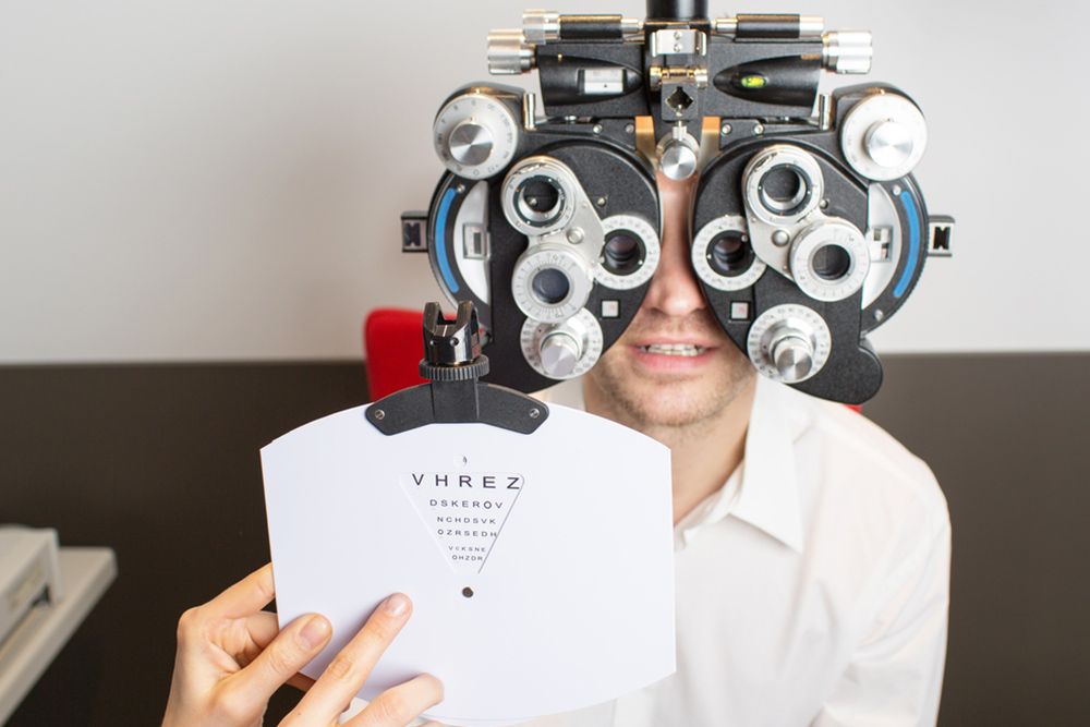 Ophthalmologist Checking The Mans Eye Using Phoropter Machine — Central Coast Eyecare In Gosford, NSW