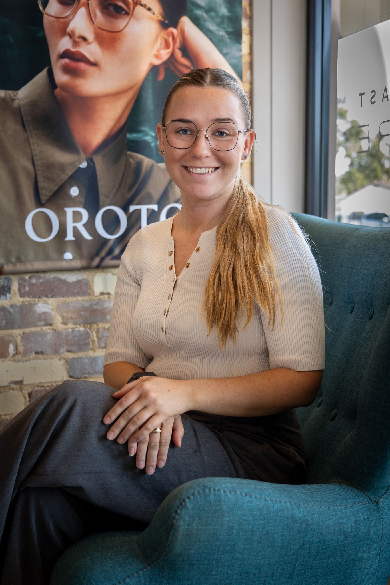 A Woman Wearing Glasses Is Sitting In A Chair — Central Coast Eyecare In Gosford, NSW