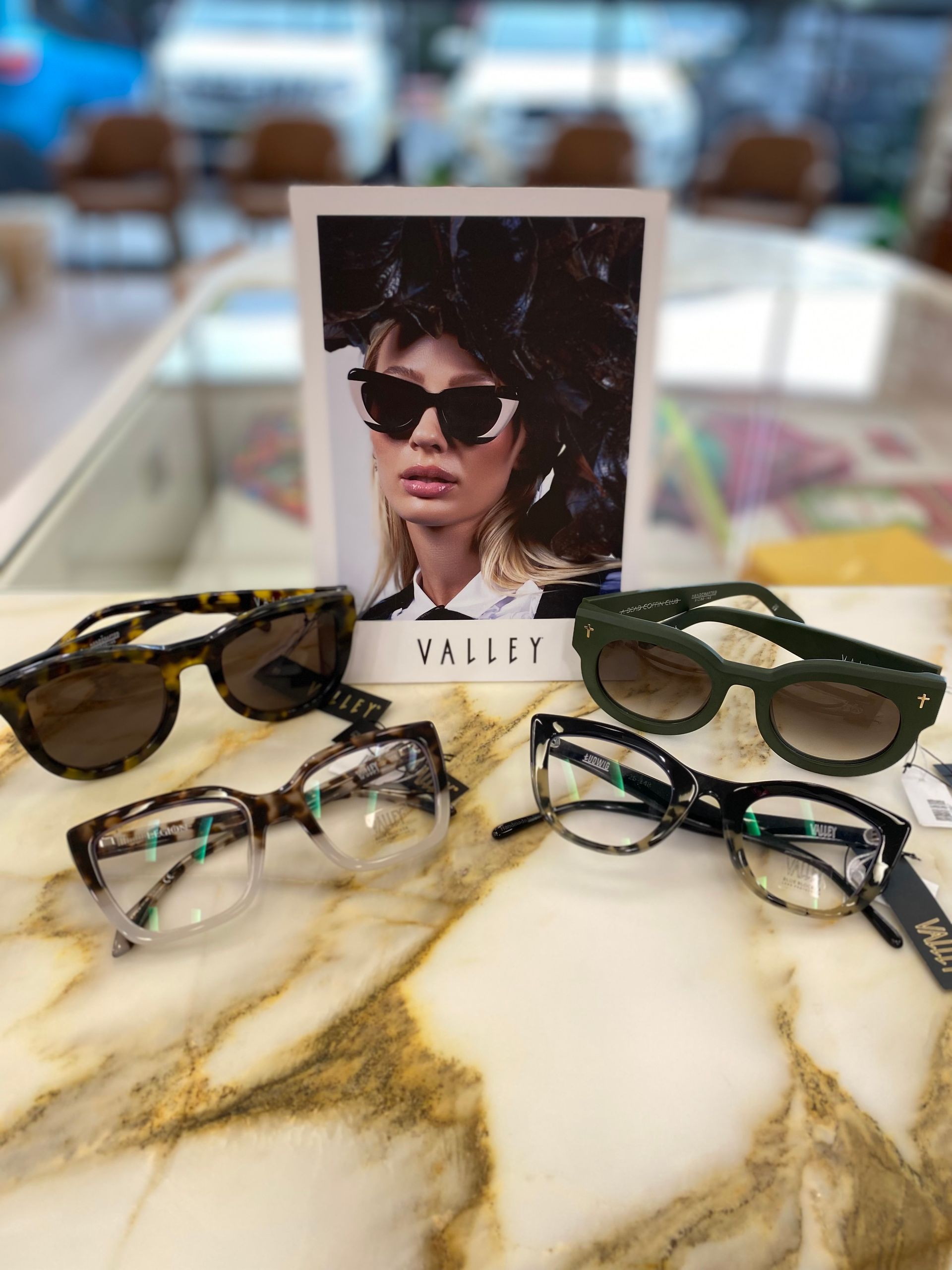 A Wall With Purple Shelves Filled With Glasses And Sunglasses — Central Coast Eyecare In Gosford, NSW
