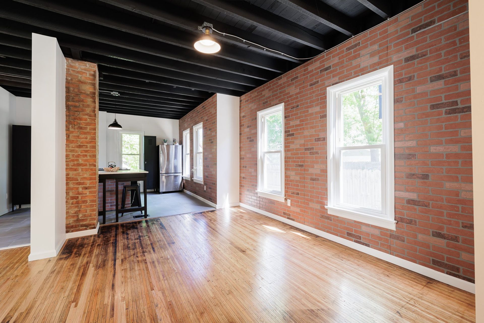 A large empty room with brick walls and hardwood floors.