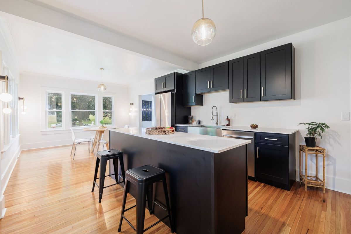 A kitchen with black cabinets and stools and a large island.