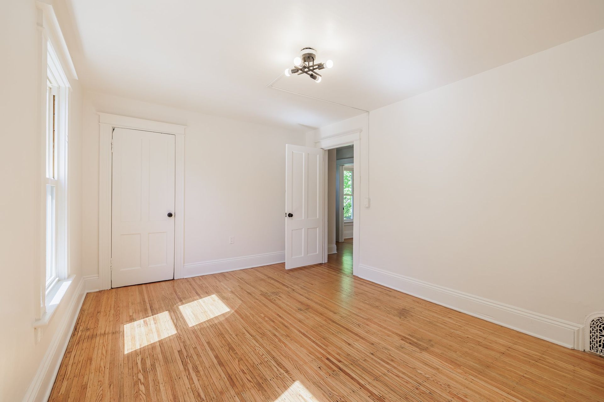An empty room with hardwood floors and white walls.