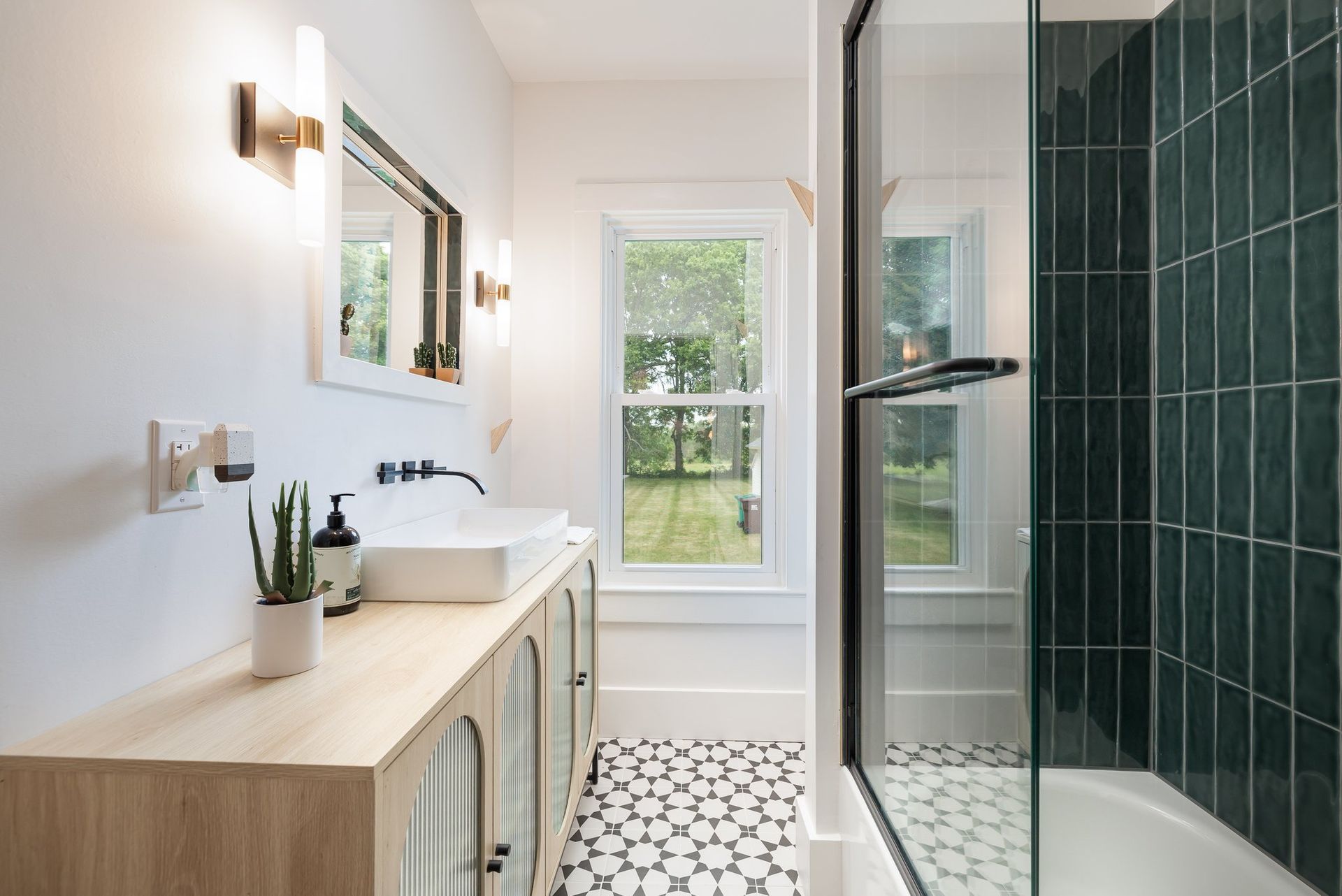 A bathroom with a sink , mirror , and walk in shower.