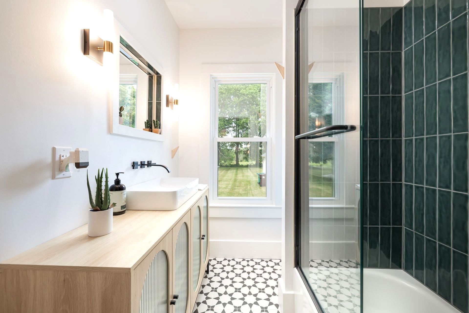 A bathroom with a walk in shower , sink , mirror and window.