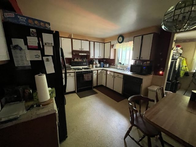 A kitchen with a black refrigerator and white cabinets