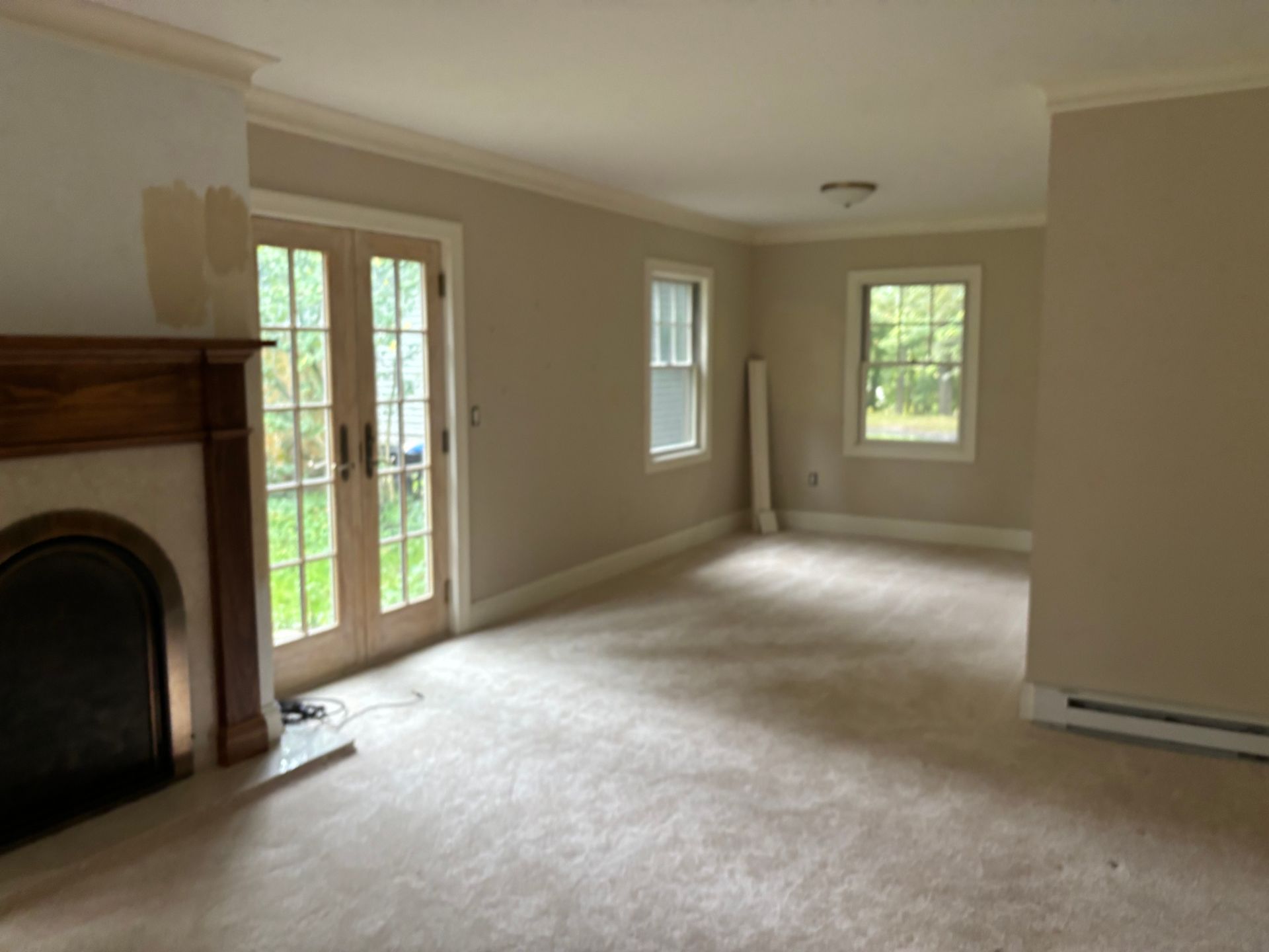 An empty living room with hardwood floors and large windows