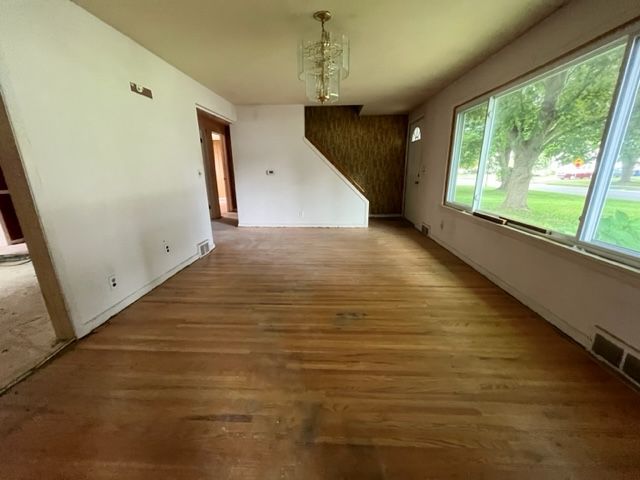 An empty living room with hardwood floors and large windows