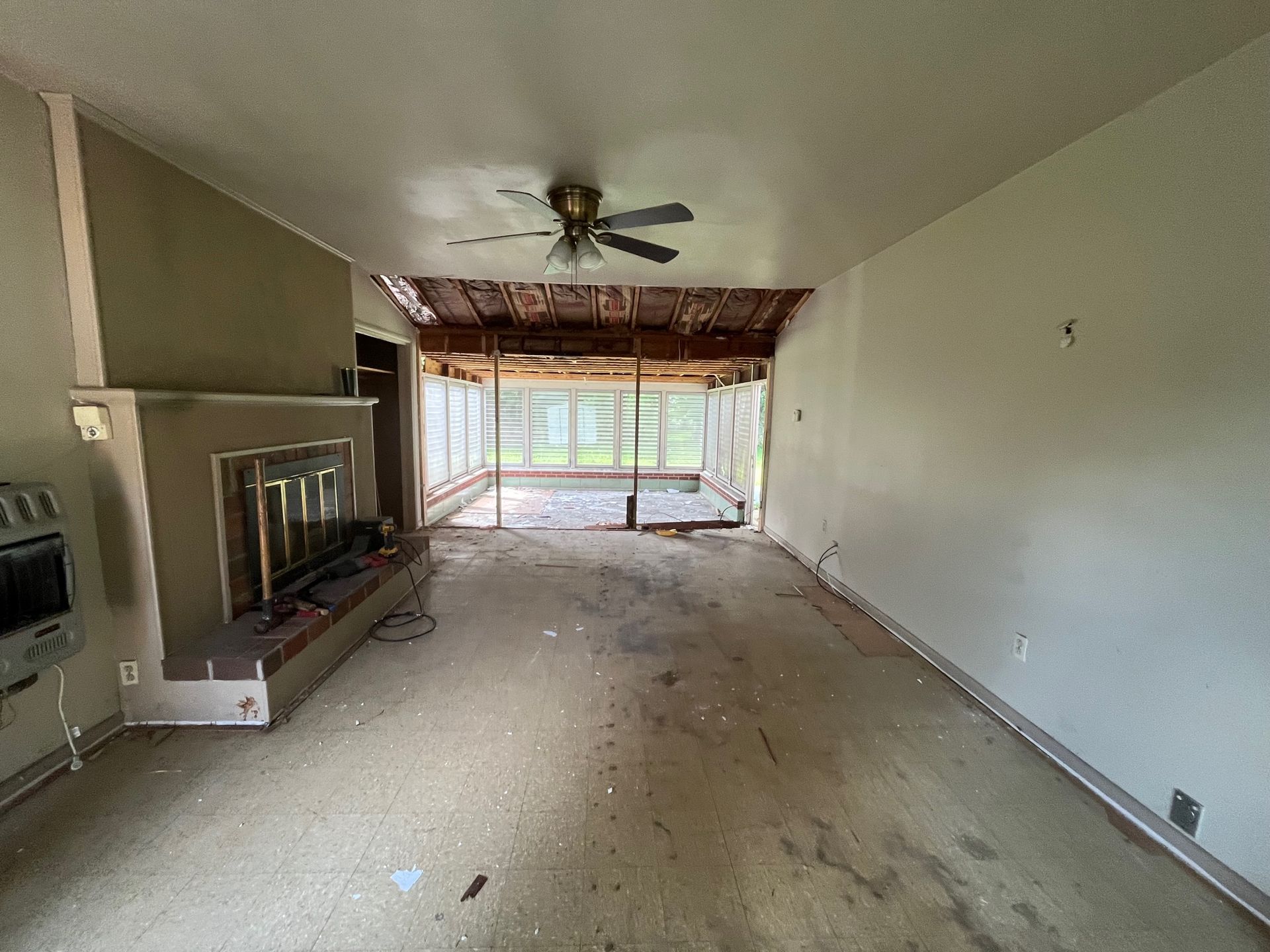 An empty living room with a fireplace and a ceiling fan.