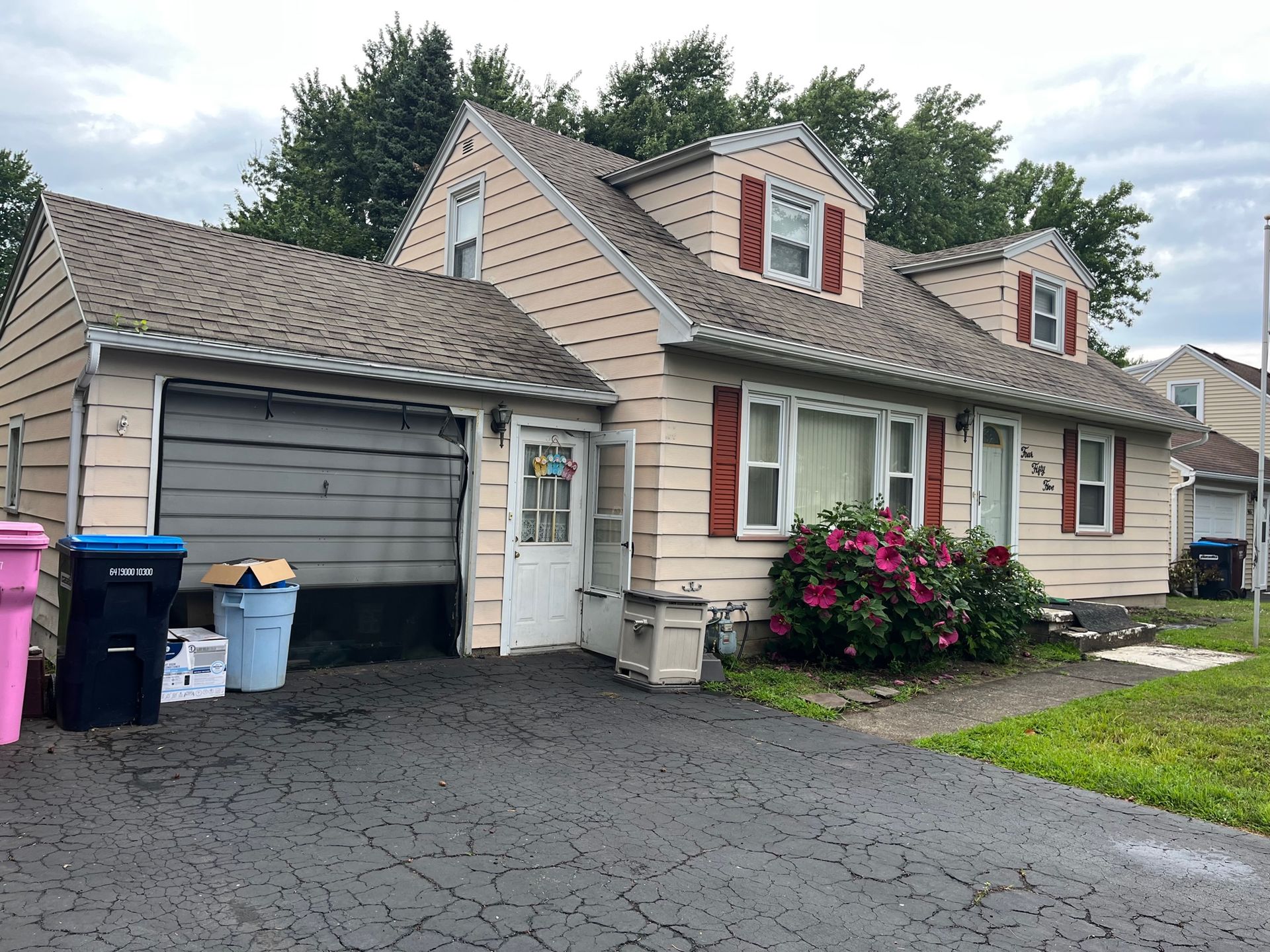 A house with a garage and trash cans in front of it