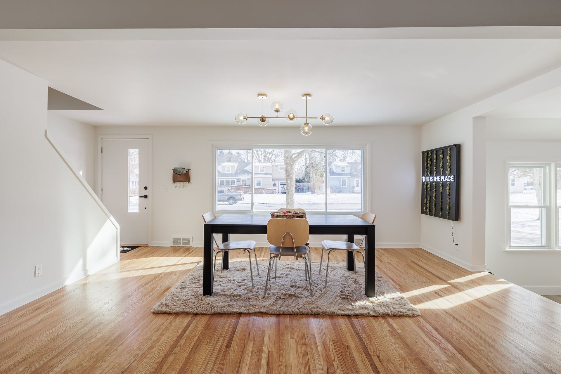 A dining room with a table and chairs and hardwood floors.