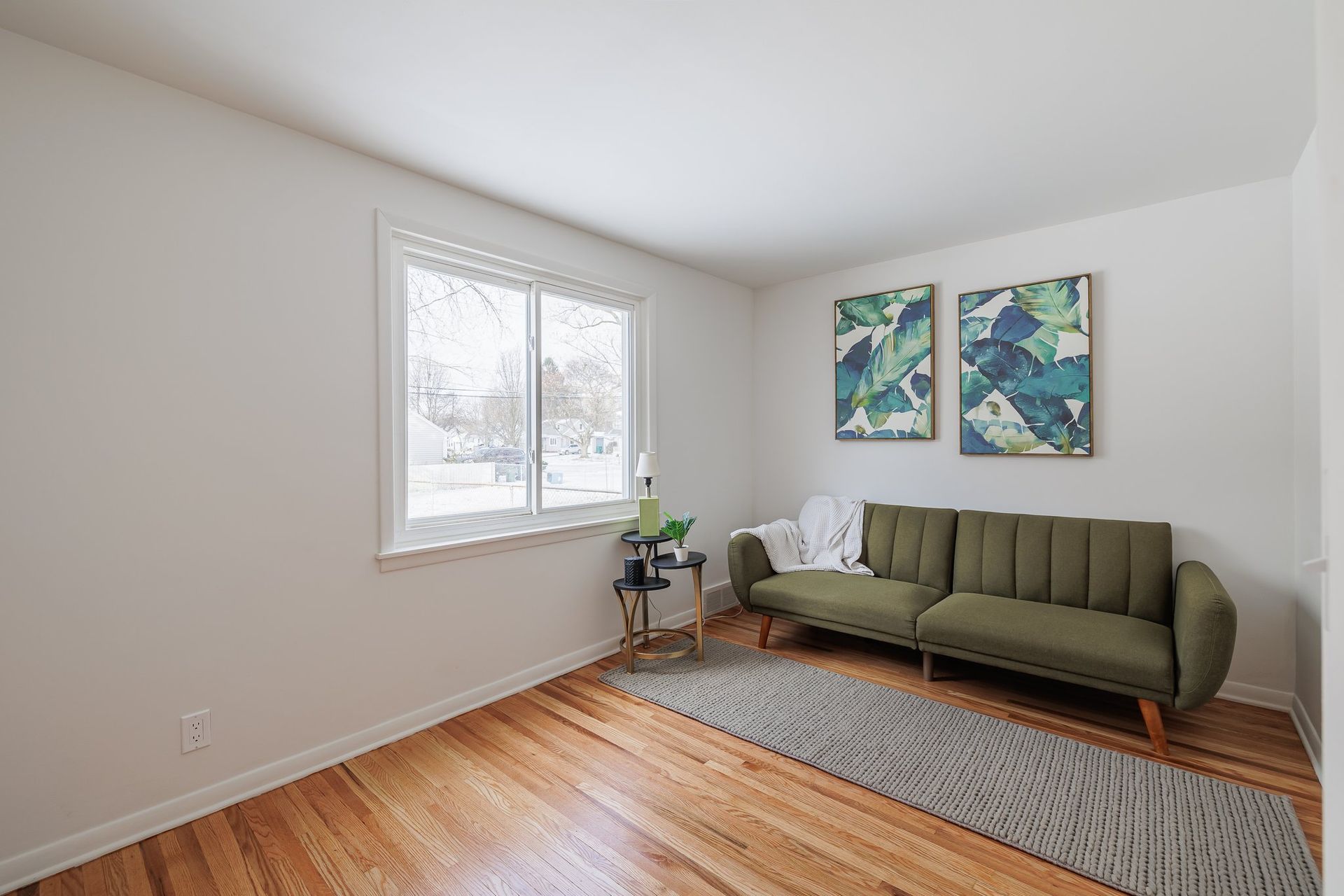A living room with a green couch and two paintings on the wall.