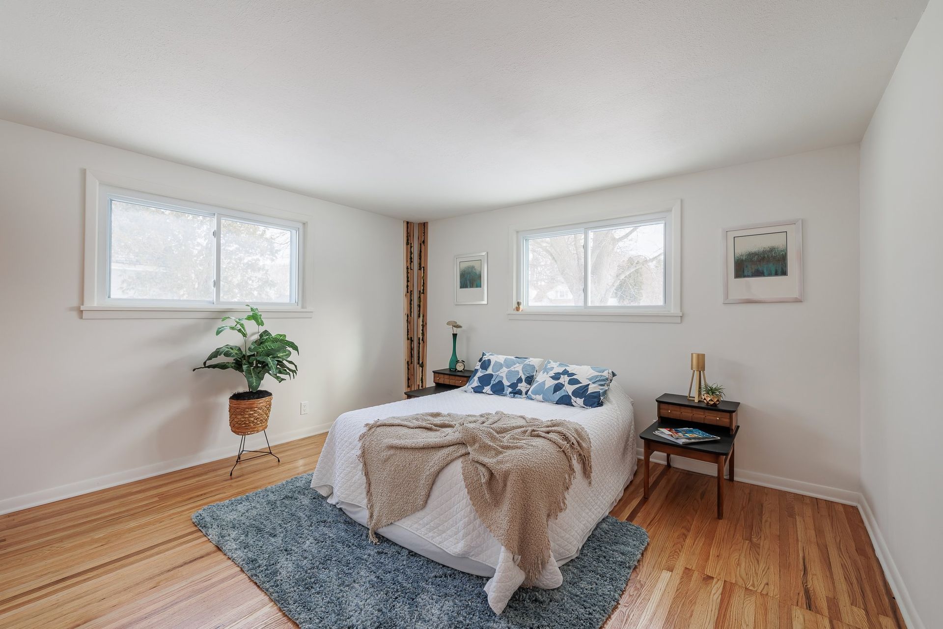 A bedroom with a bed , nightstand , rug and windows.