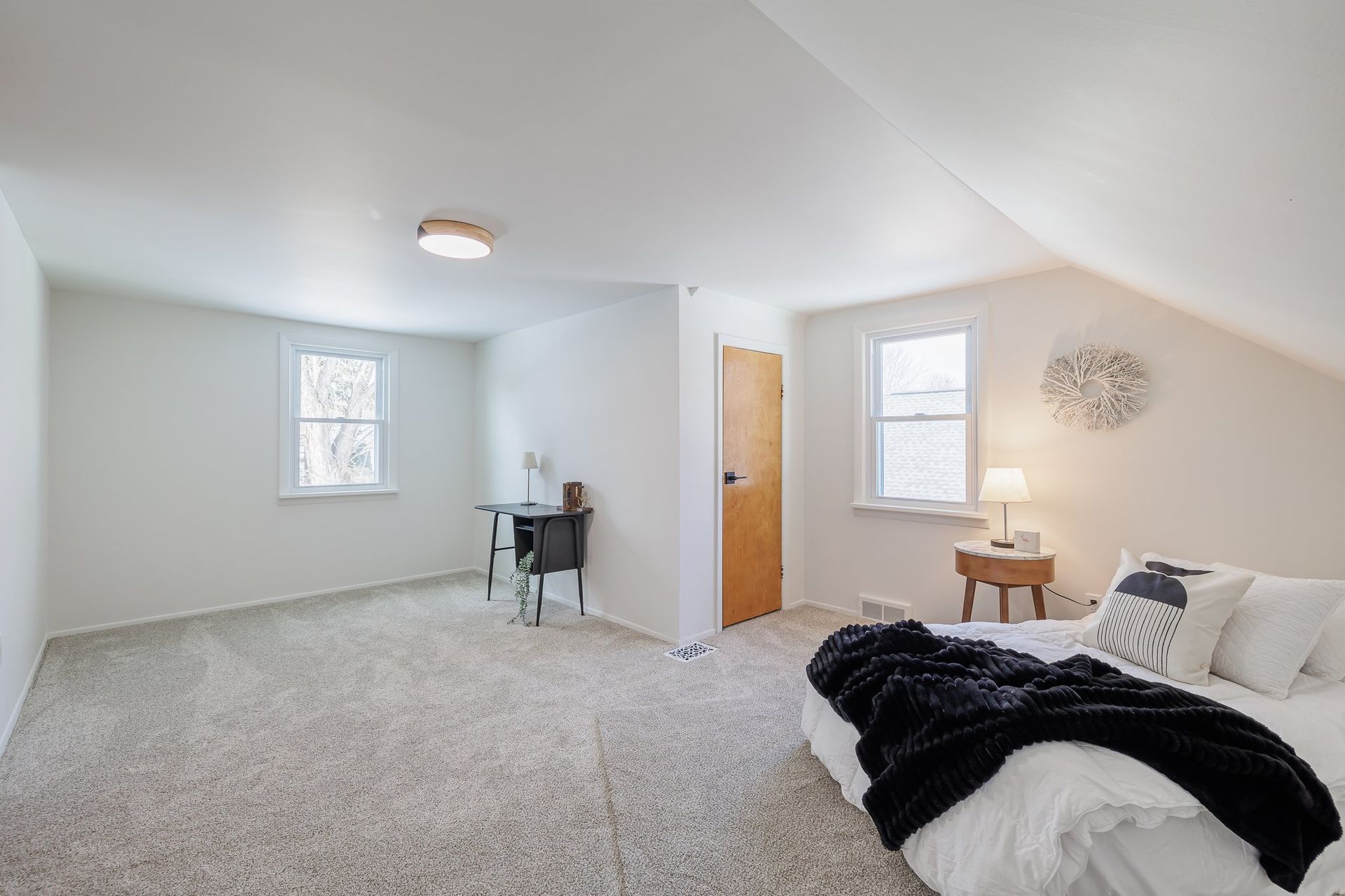 A bedroom with a bed , desk , and window.