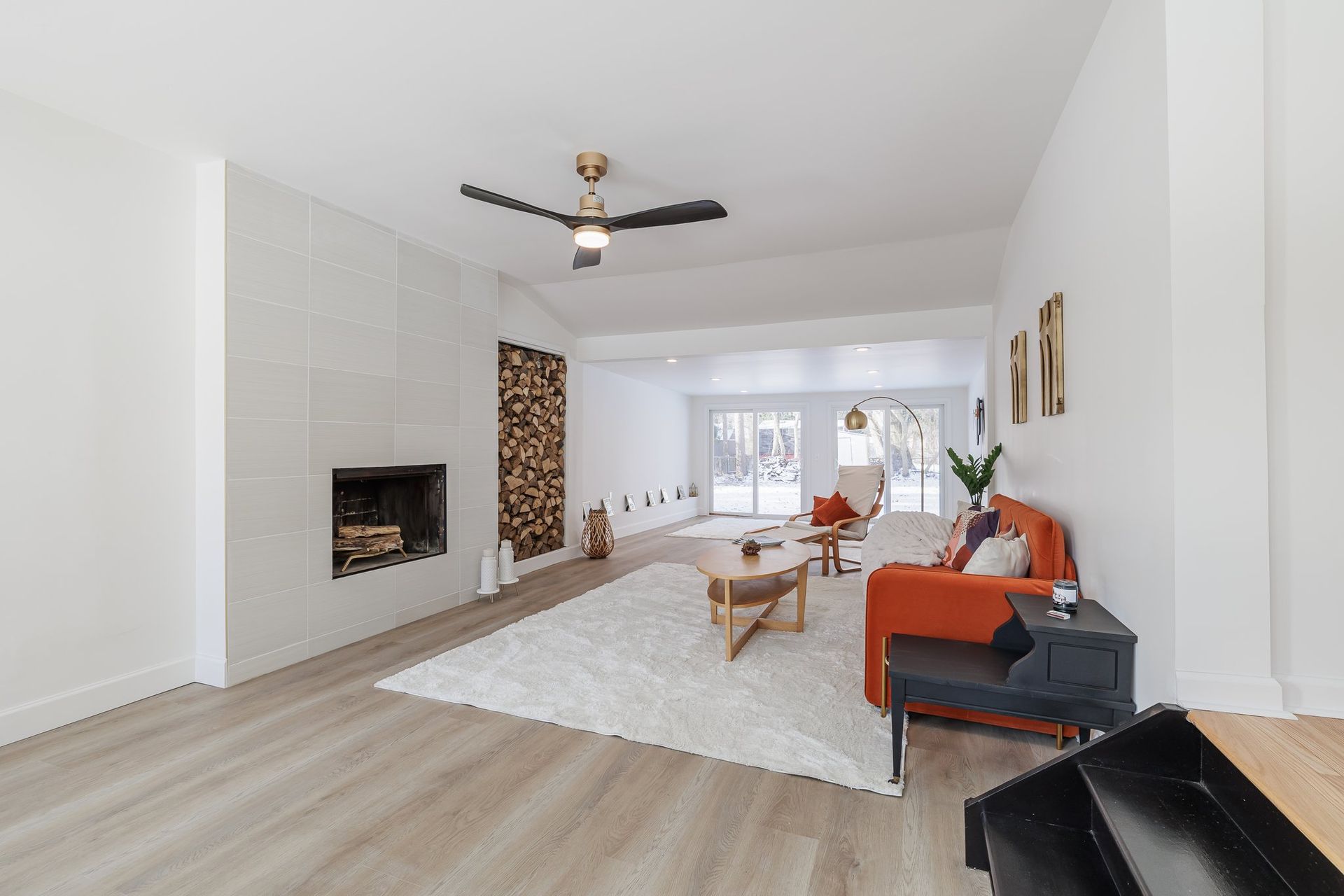 A living room with a couch , fireplace and ceiling fan.