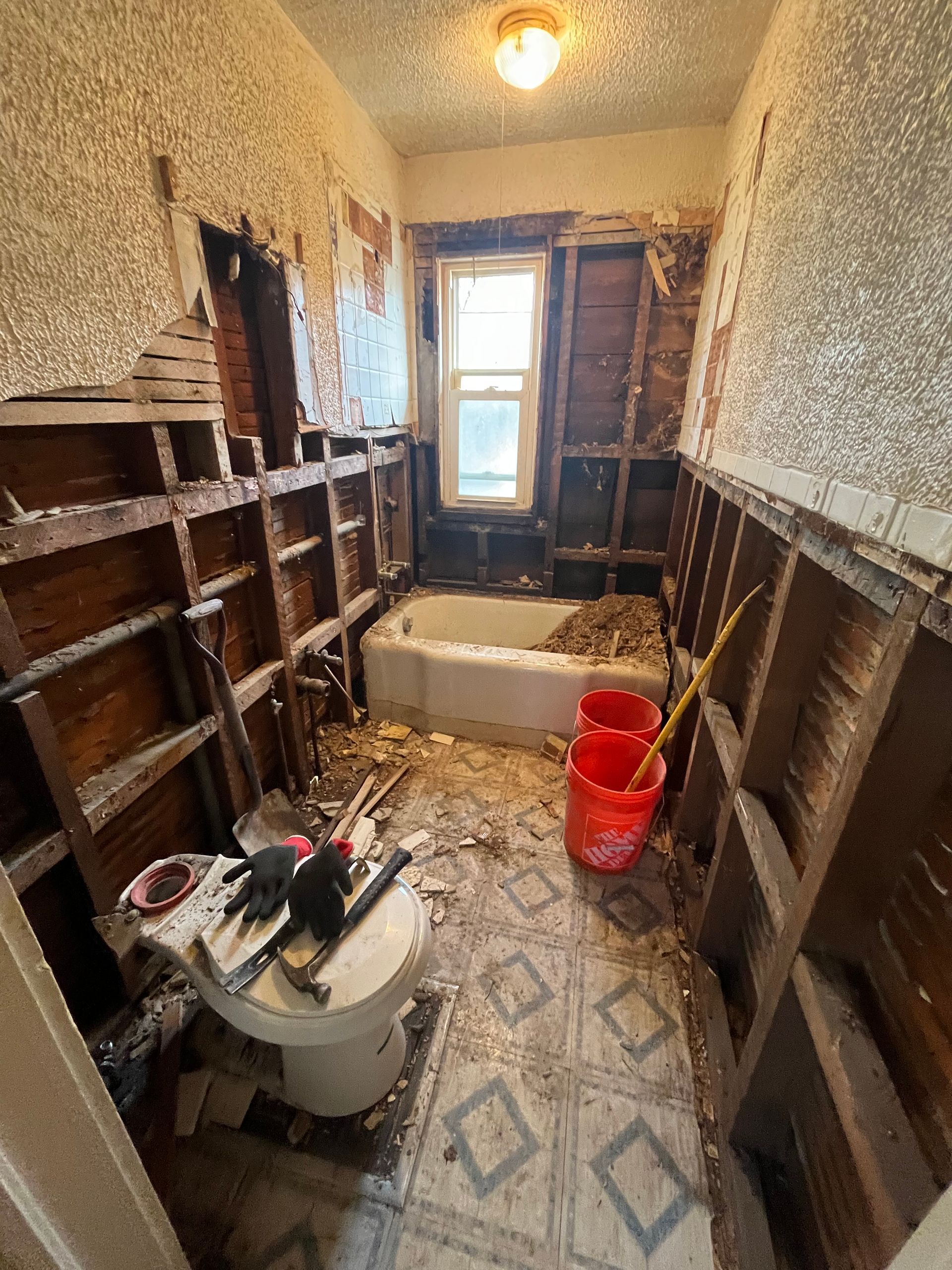 A bathroom is being remodeled with a toilet , bathtub , and shelves.