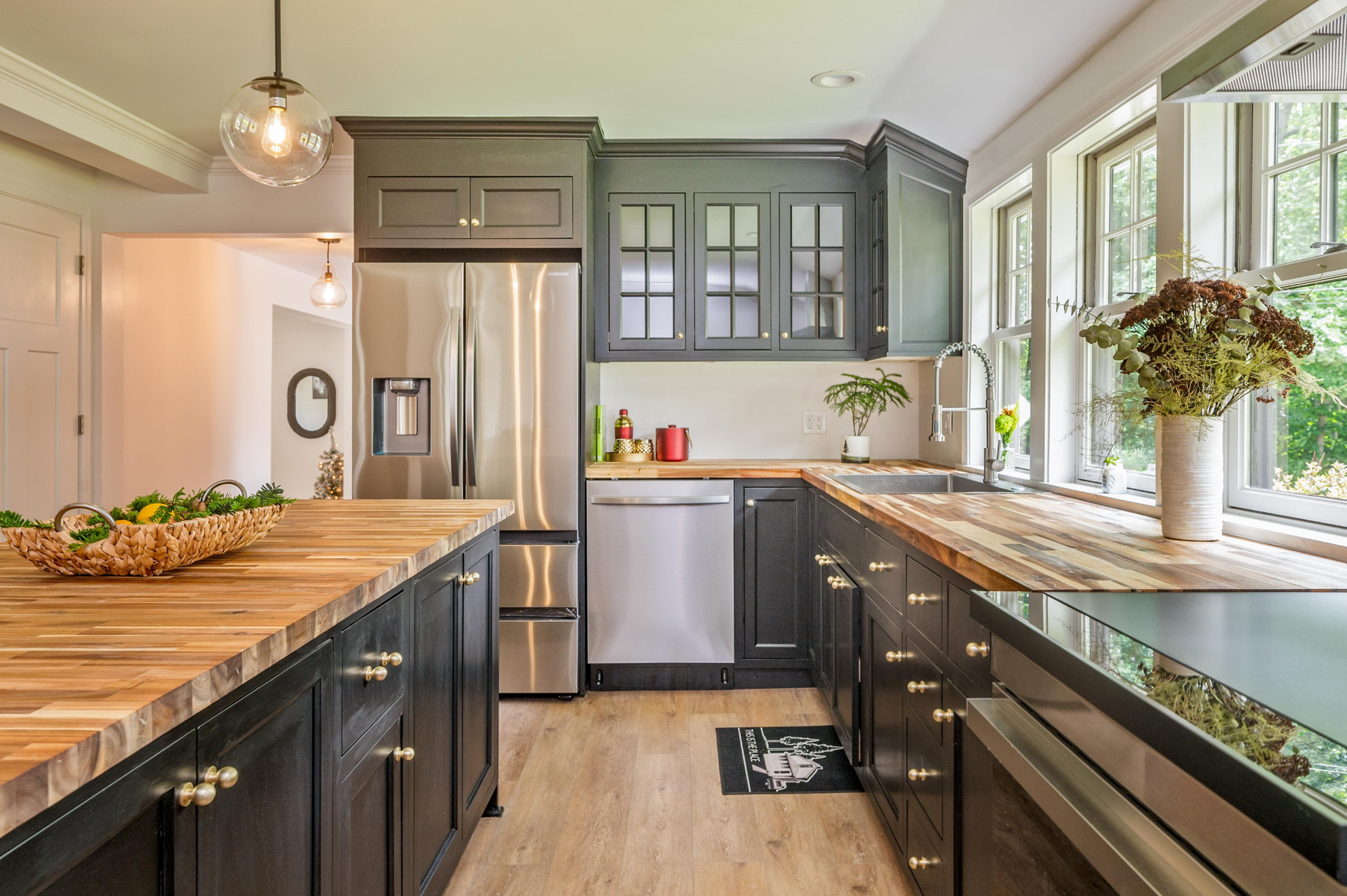 A kitchen with black cabinets , stainless steel appliances , and wooden counter tops.