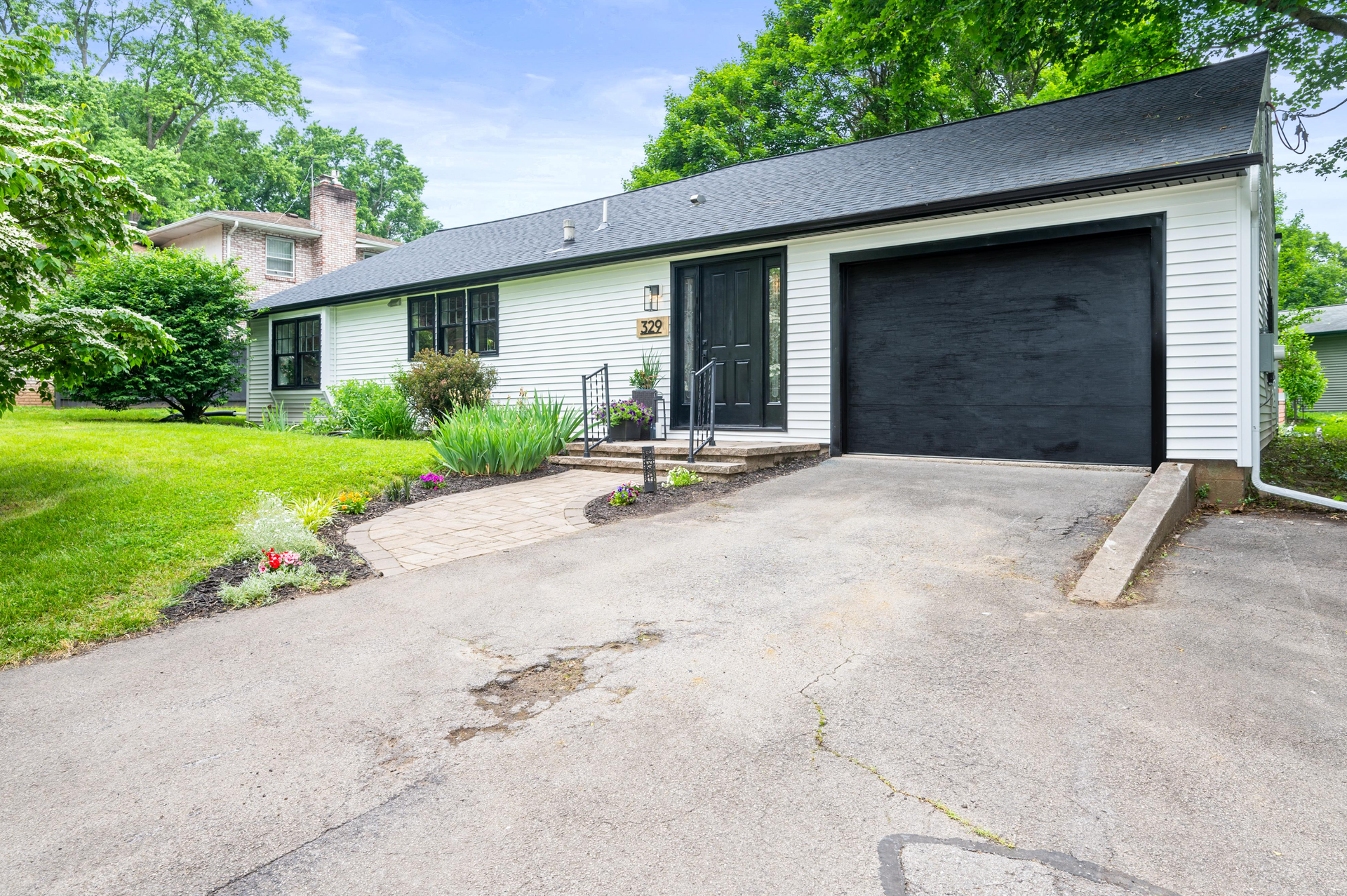 A white house with a black garage door is for sale.