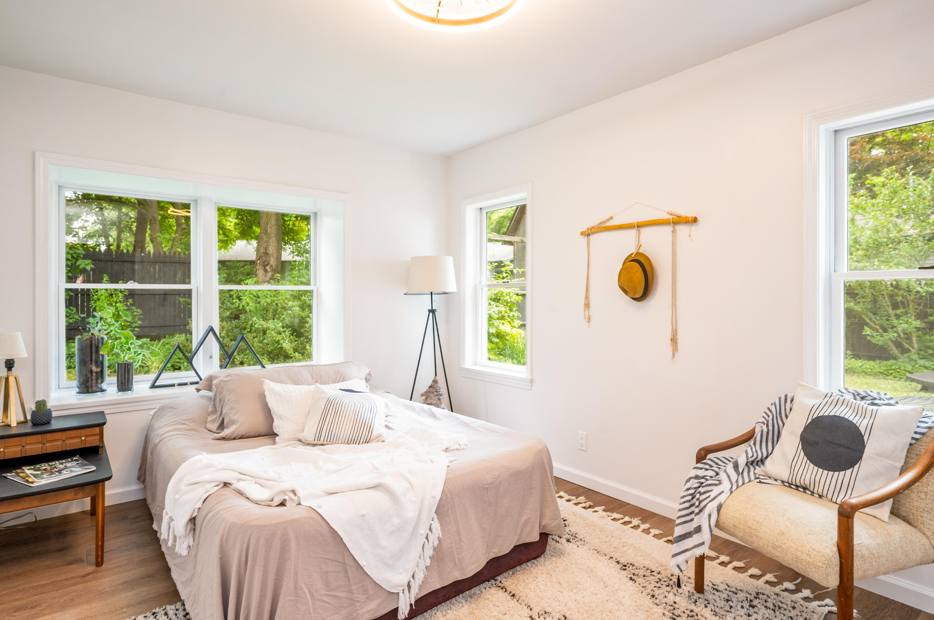 A bedroom with a bed , chair , desk and windows.