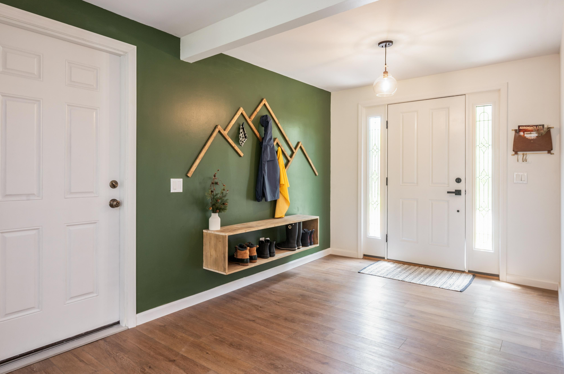 A hallway with a green wall and a wooden coat rack.