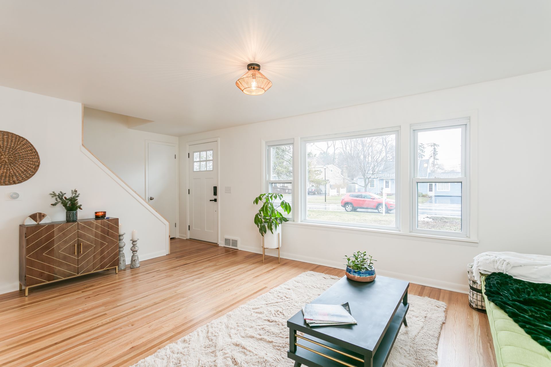 A living room with hardwood floors , a coffee table , a couch , and a dresser.