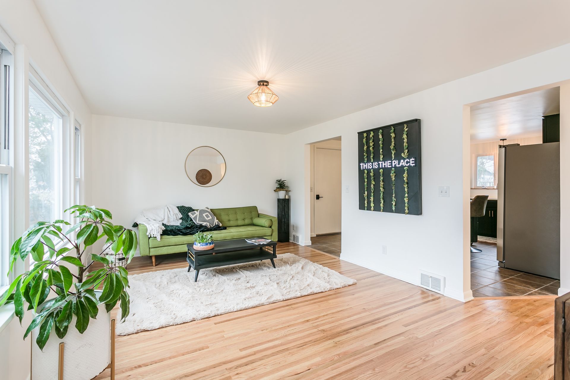 A living room with a green couch , a coffee table , and a plant.