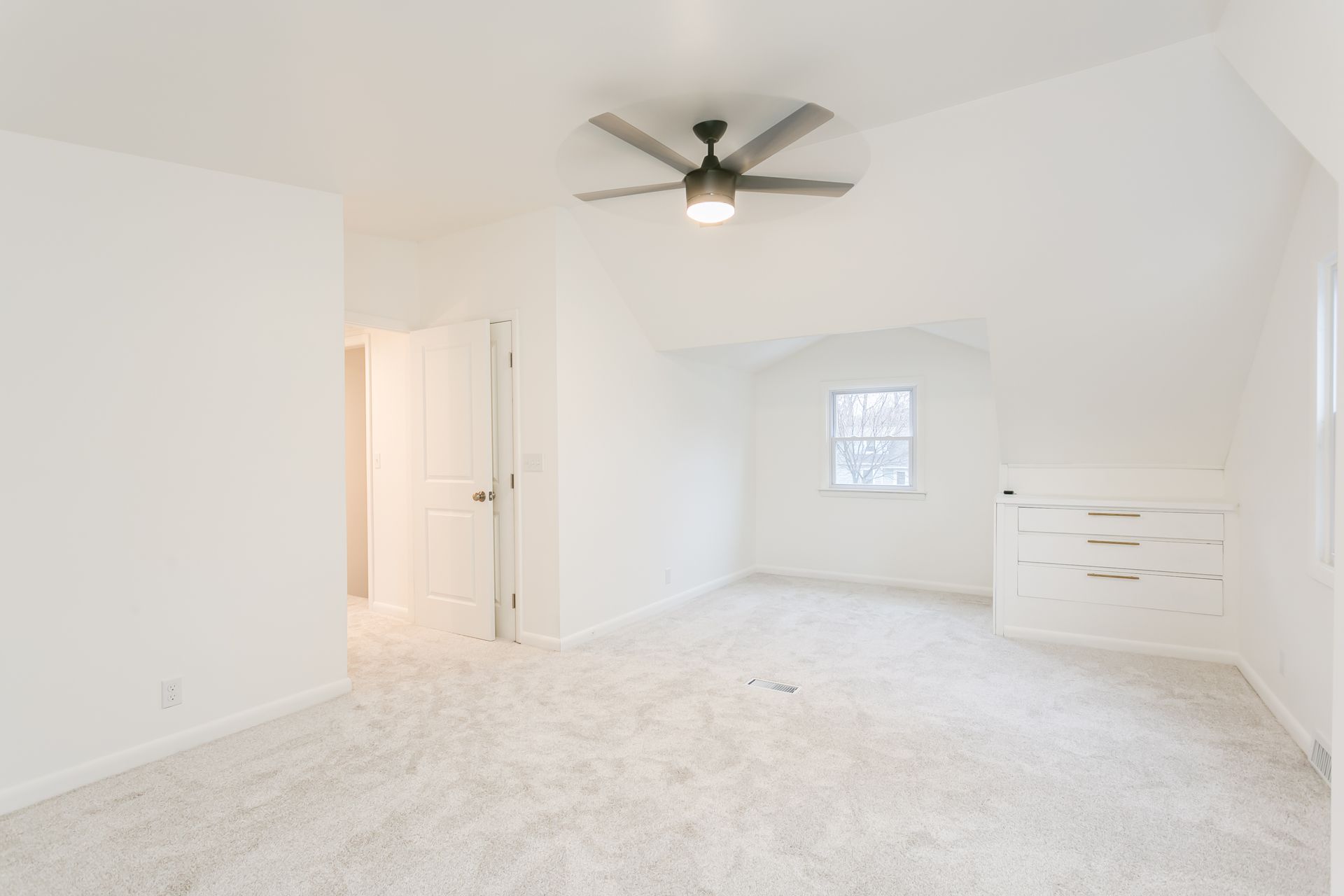 An empty bedroom with a ceiling fan and a window.