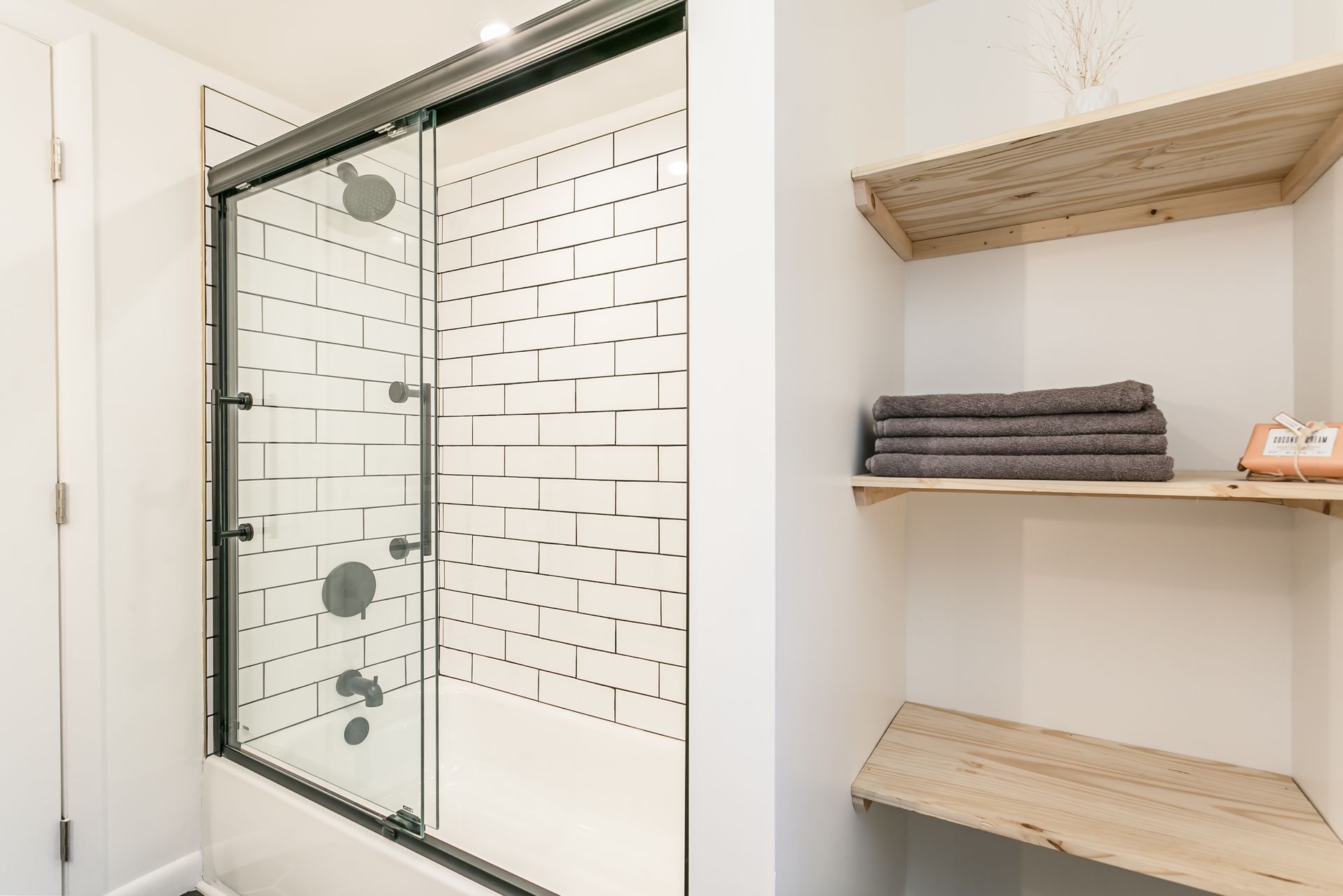 A bathroom with a shower and a shelf with towels on it