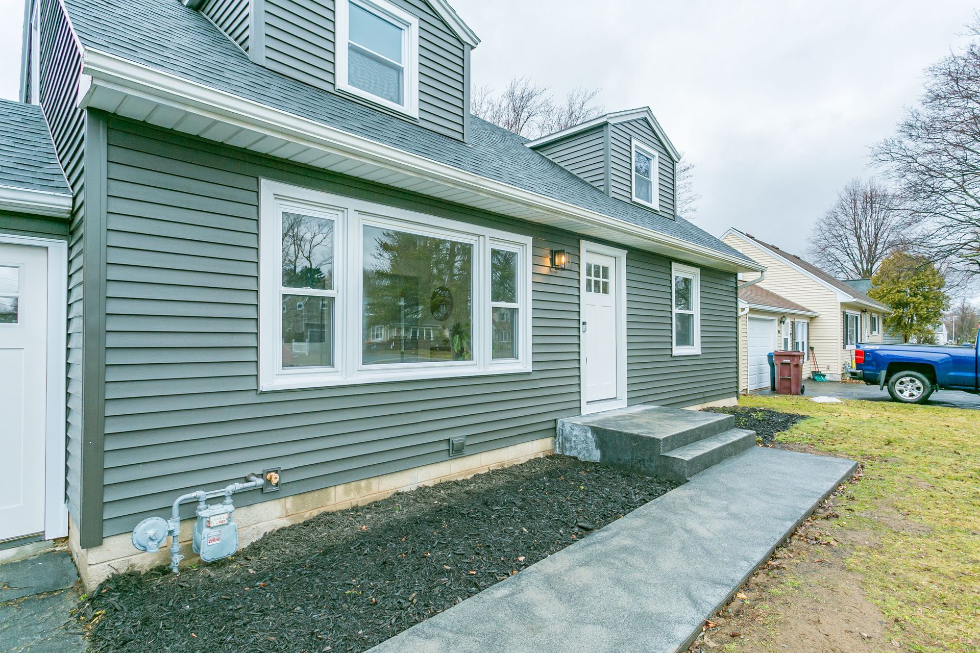 The front of a house with a blue truck parked in front of it.