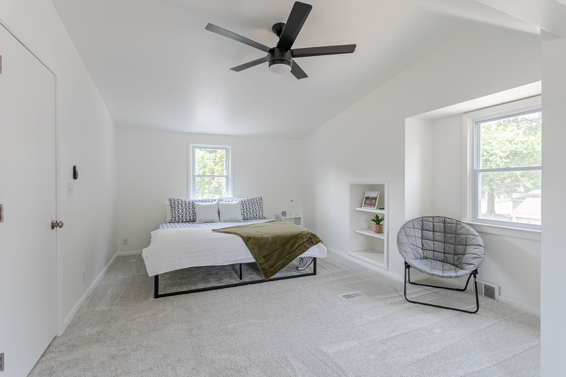 A bedroom with a bed , chair and ceiling fan.