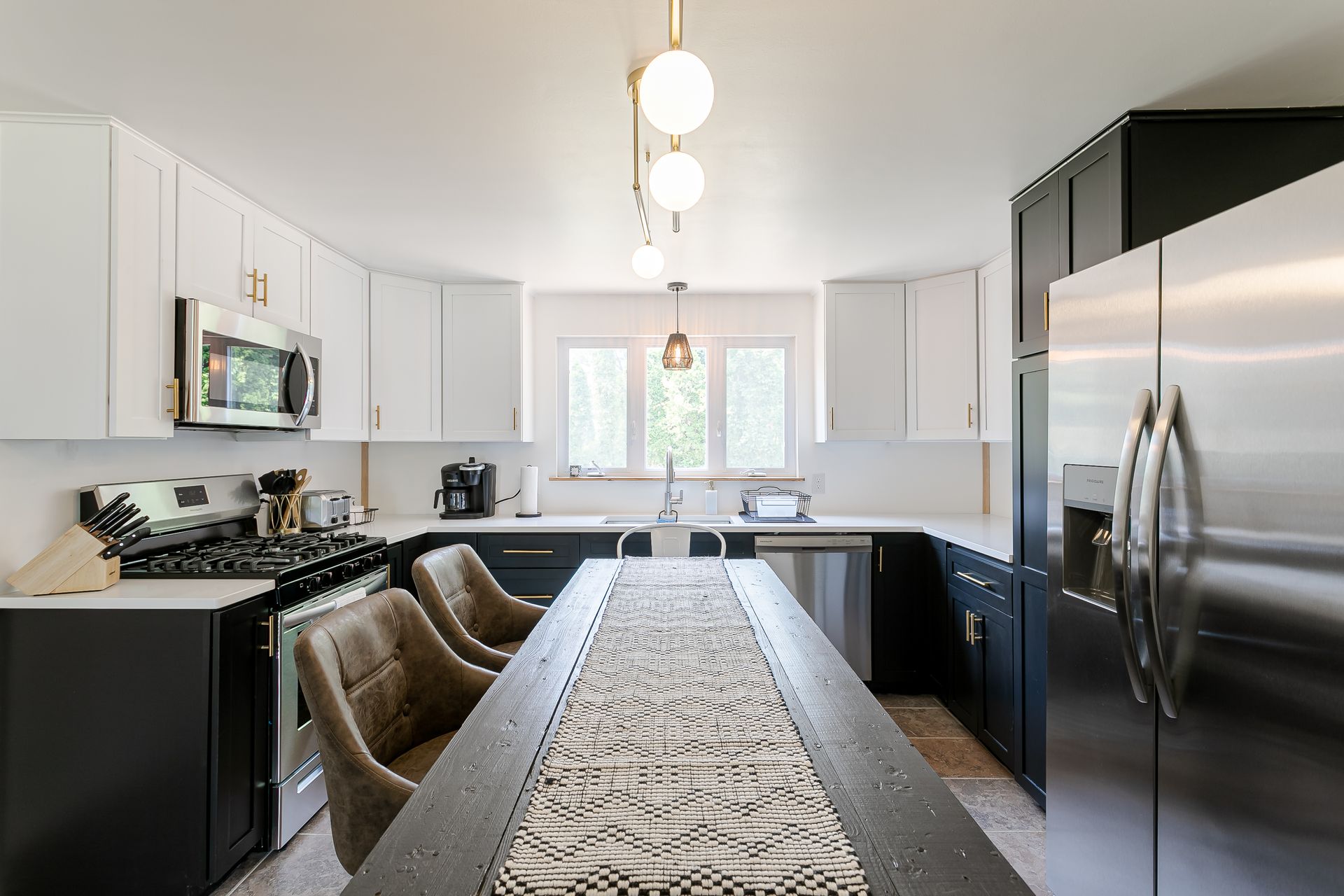 A kitchen with stainless steel appliances and a long table.