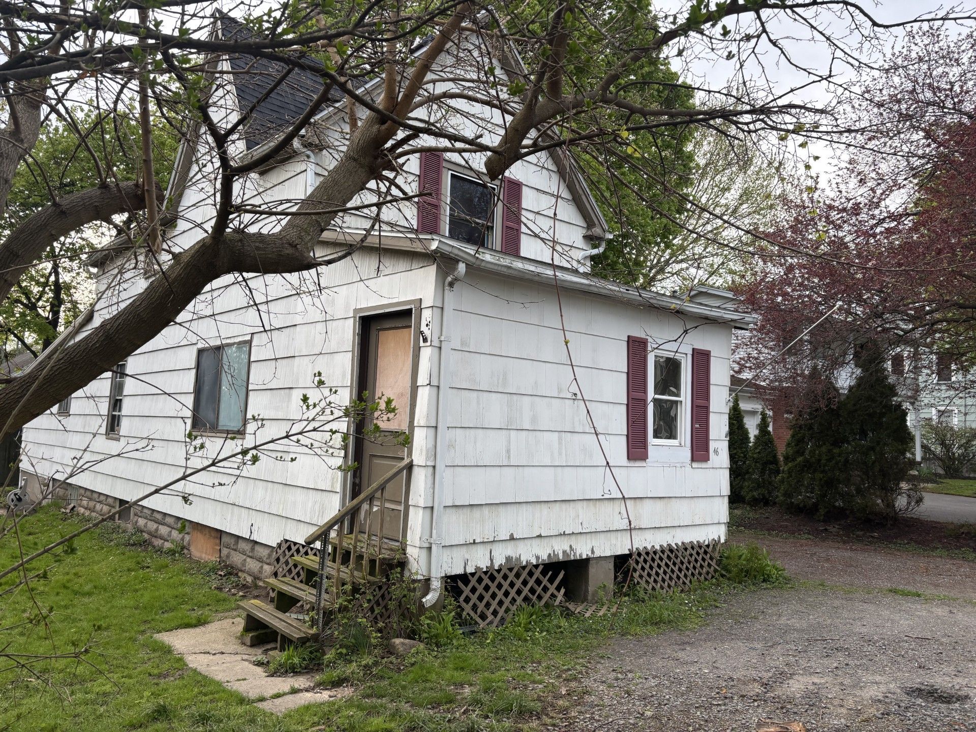 A white house with a red door and a ladder in front of it.