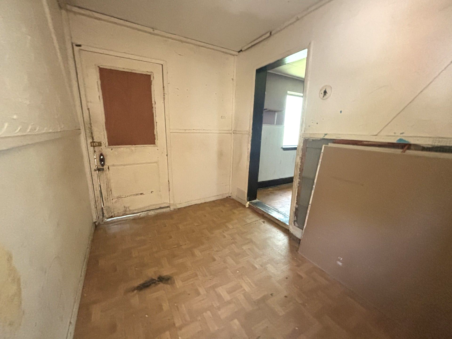 A room with peeling paint on the walls and a sink in it.