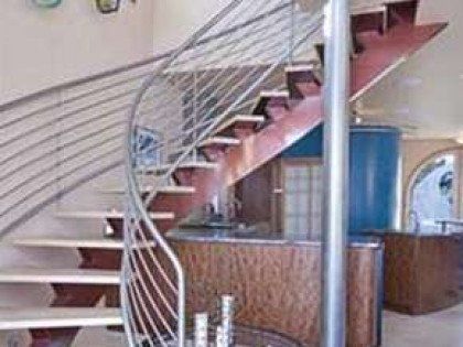 A spiral staircase with a stainless steel railing in a living room.