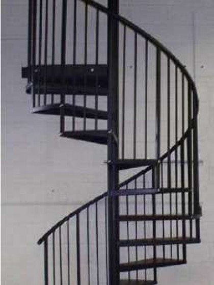 A black spiral staircase is against a white wall.