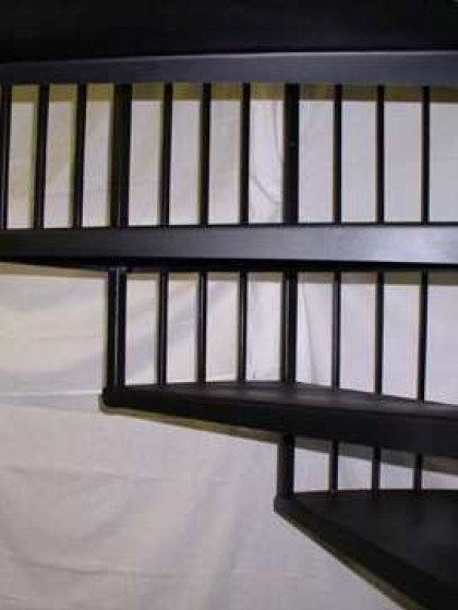 A spiral staircase with a black railing is sitting on a white surface.