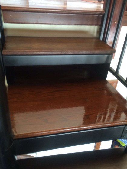 A close up of a wooden staircase with a black railing