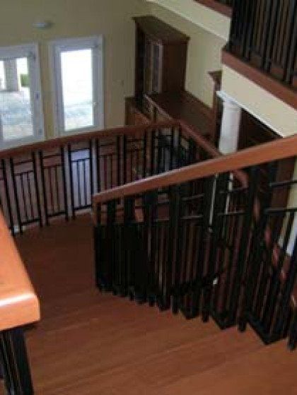 A wooden staircase with a black railing in a house.