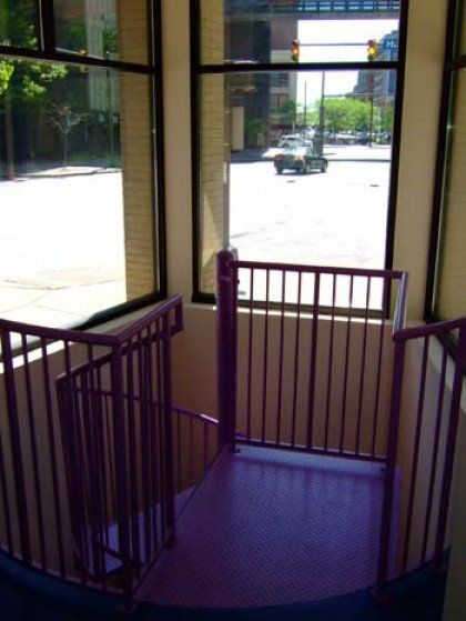 A spiral staircase with a purple railing and a window