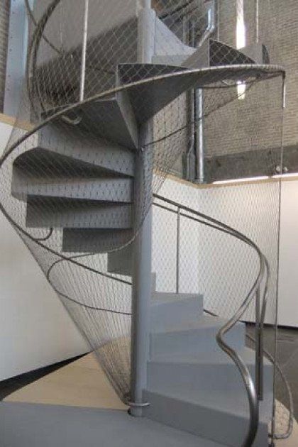 A spiral staircase with a stainless steel railing
